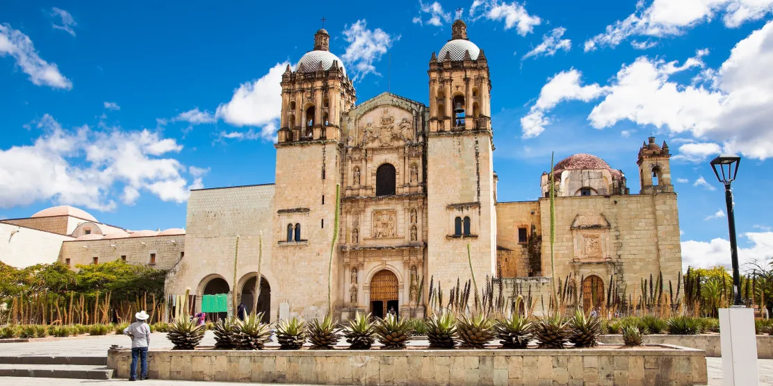Colorful colonial buildings and a historic church in Oaxaca, Mexico.