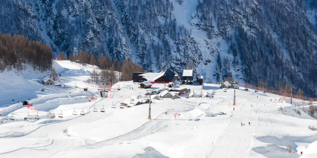 Snow-covered ski slopes and chairlifts at Madesimo ski resort in Italy.
