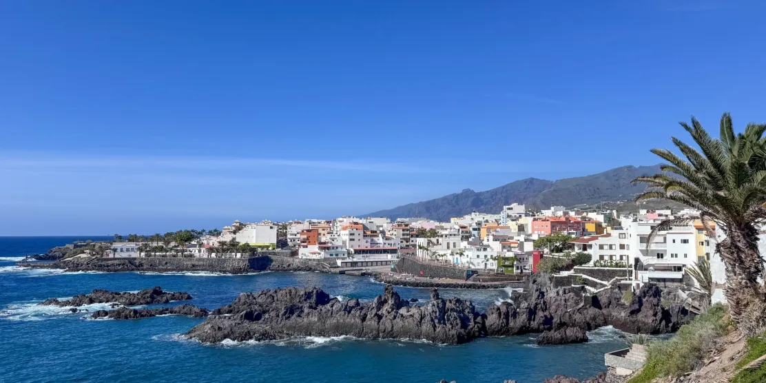 Tenerife coast in December with volcanic rocks, blue ocean and a seaside town