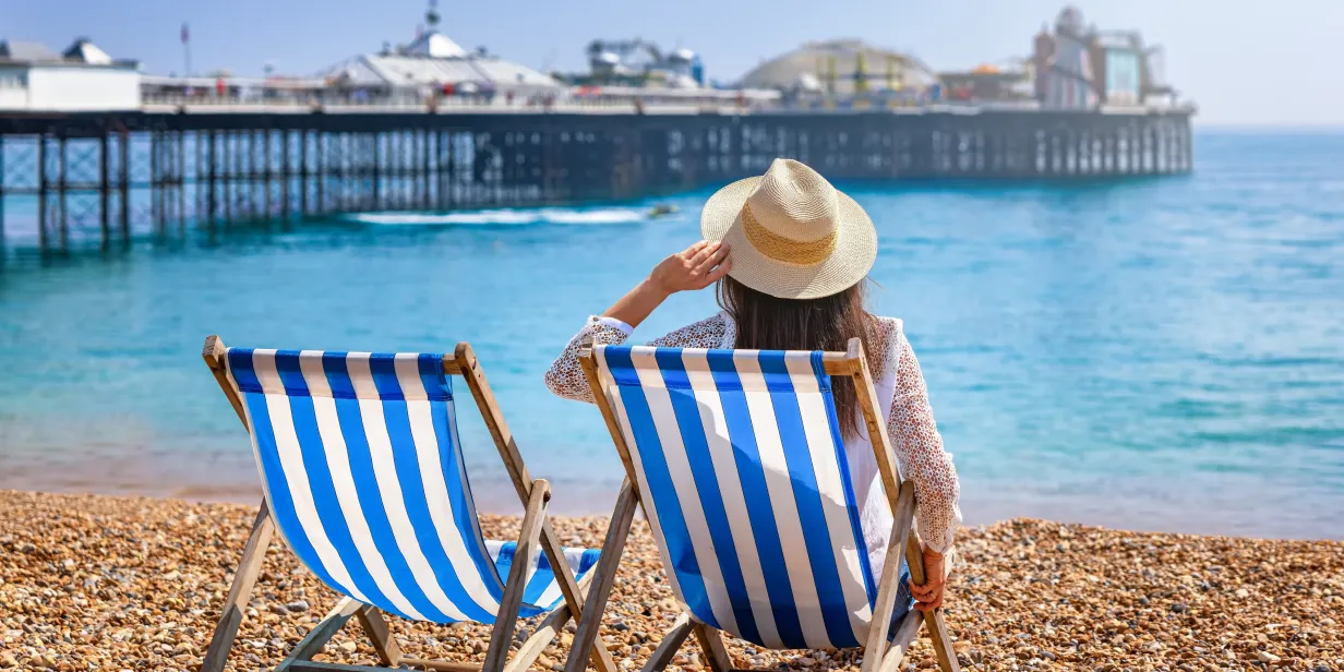 Tourist woman sitting on a deckchair in Brigton, England.